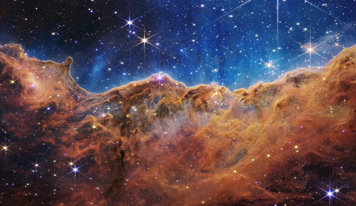 Nebula Carina: Bintang-bintang berkilau dengan latar belakang nila di atas awan gas perunggu berkarat