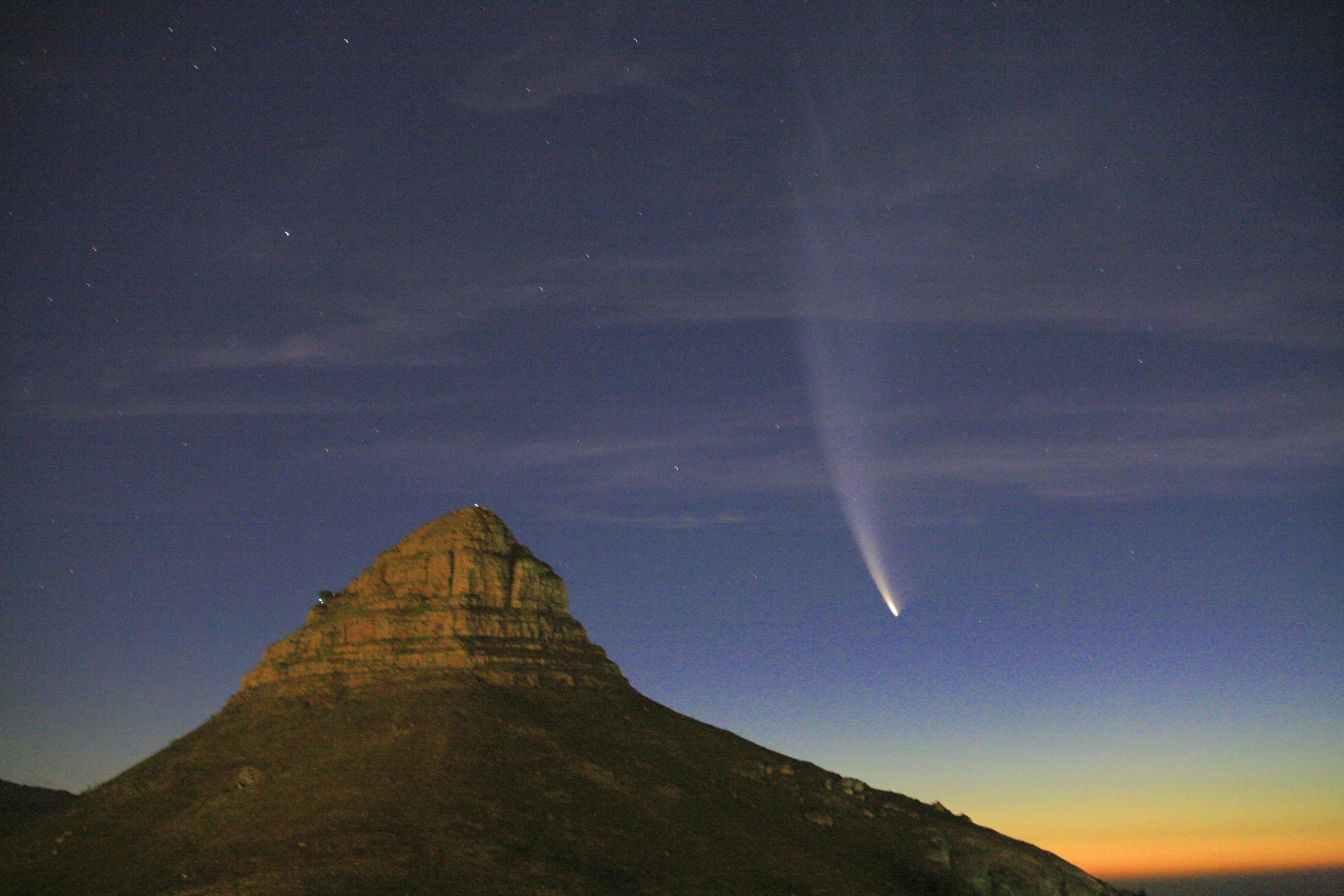 Sebuah komet terang di atas gunung saat matahari terbenam