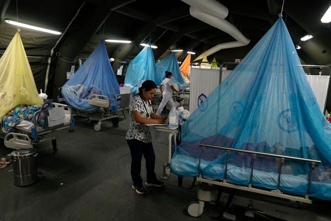 Seorang dokter menulis resep saat pasien demam berdarah terbaring di tempat tidur di tenda darurat Kementerian Kesehatan di Piura, Peru, Sabtu, 3 Juni 2023. Demam berdarah, penyakit virus yang ditularkan oleh nyamuk, menyebabkan gejala mirip flu, seperti seperti nyeri otot dan demam. .  (Foto AP/Martin Mejia)