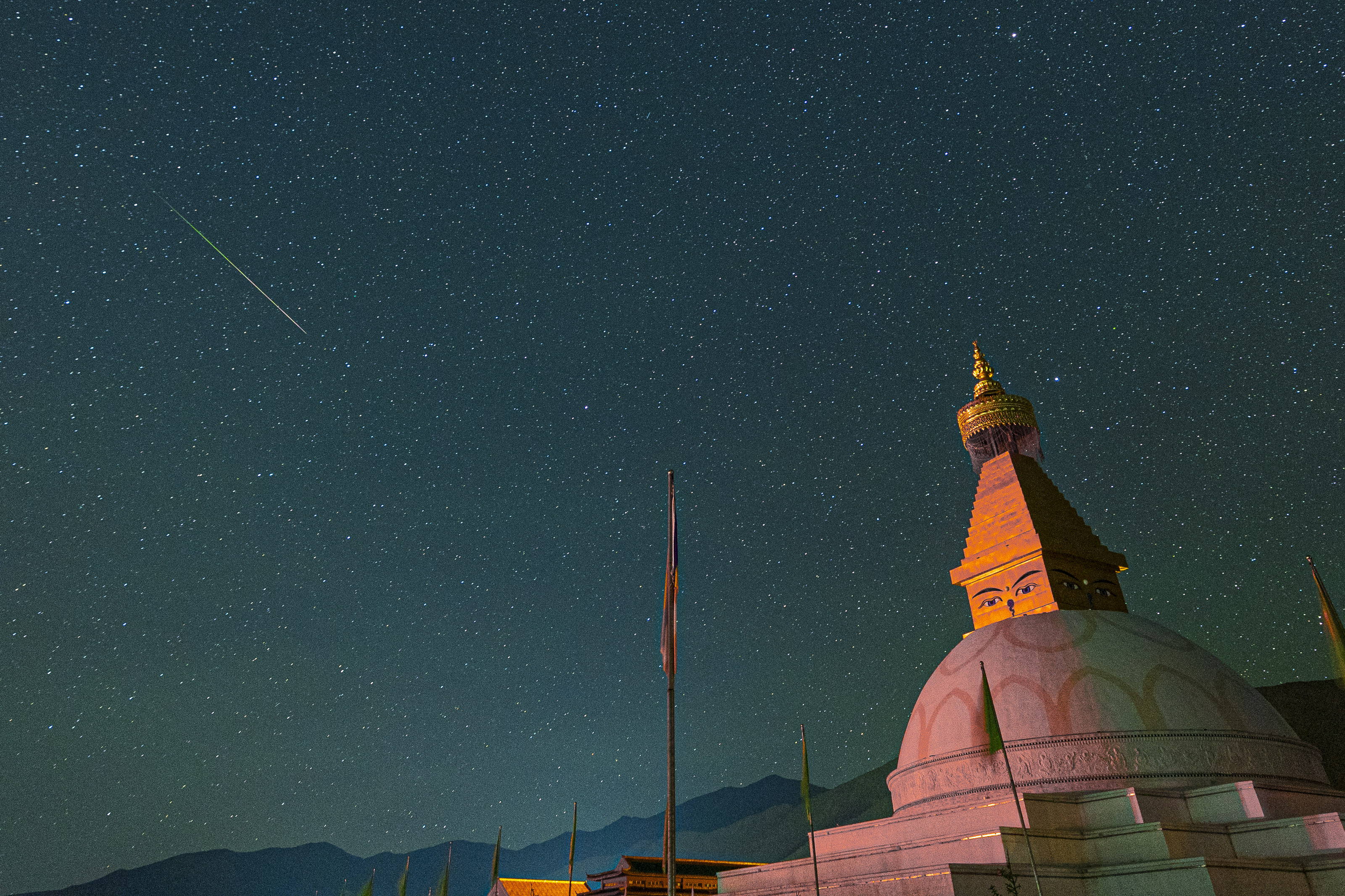 Sebuah meteor Perside melesat melintasi langit di atas sebuah bangunan besar berkubah.