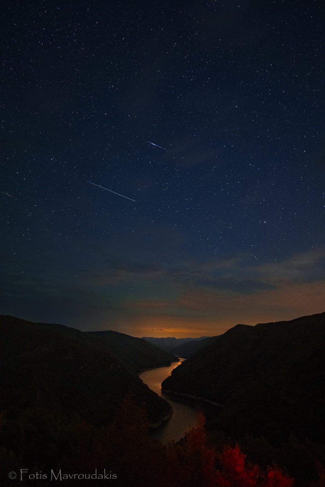 Meteor Perseid melesat melintasi langit di atas sungai dan pegunungan.