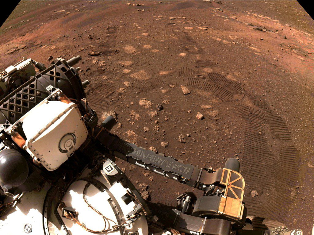 Bekas tapak roda tertinggal di tanah Kawah Jezero di Mars, saat penjelajah Mars milik NASA, Perseverance, berjalan di permukaan Mars untuk pertama kalinya, dalam foto yang diambil pada 4 Maret 2021 ini. 