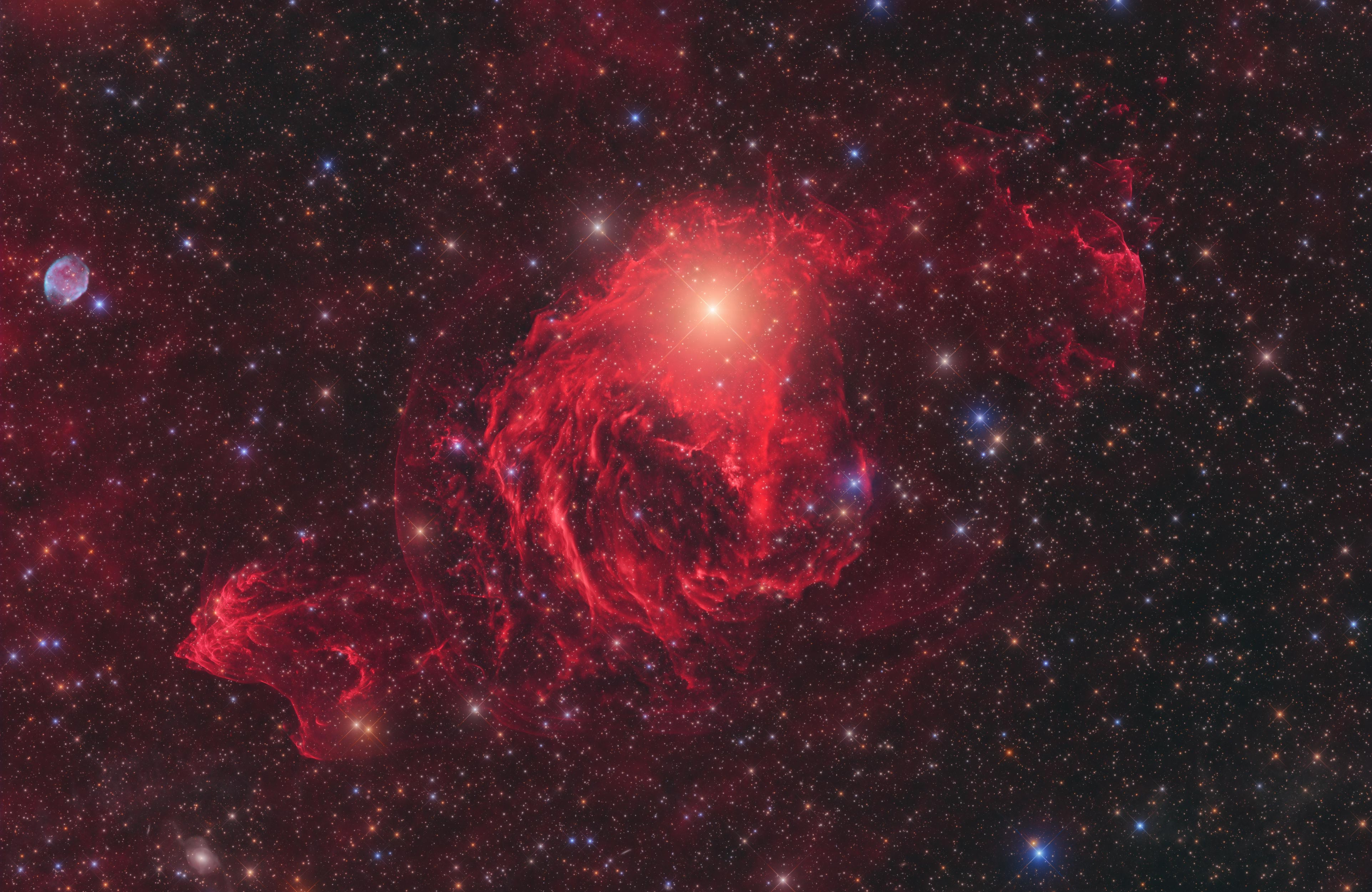 Nebula gas merah berkeliaran di sekitar bintang terang di luar angkasa.