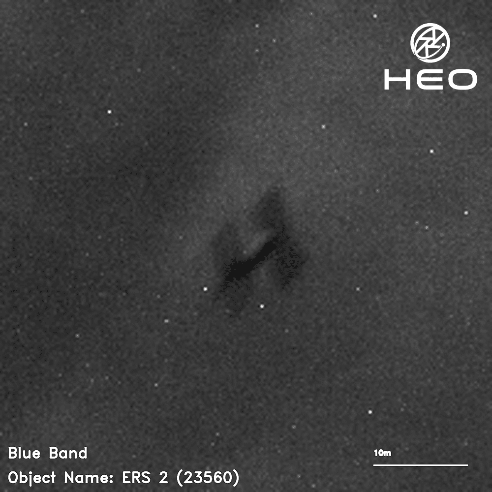 Gambar hitam putih buram dari satelit berbentuk H dengan latar belakang beberapa lusin bintang