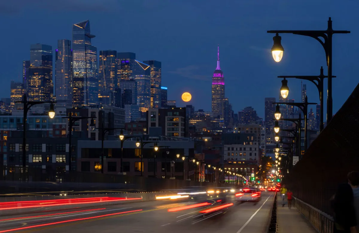 Bulan panen super di pusat kota Manhattan dan Empire State Building di New York City, AS. Foto latar depan menunjukkan lalu lintas di sepanjang 14th Street Bridge, 17 September 2024. Foto oleh Gary Hirschorn/Getty Images