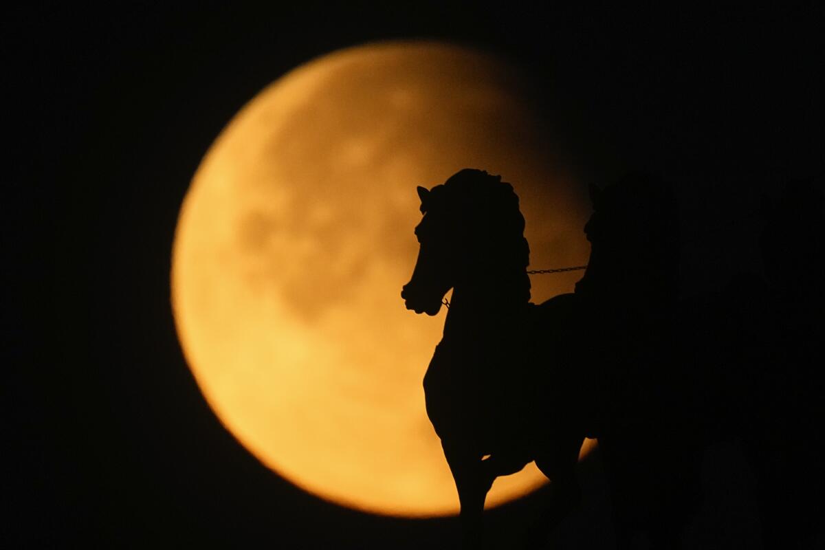 Supermoon muncul di belakang patung kuda di puncak Arc de Triomphe saat gerhana bulan sebagian di Moskow, Rusia, 18 September 2024.